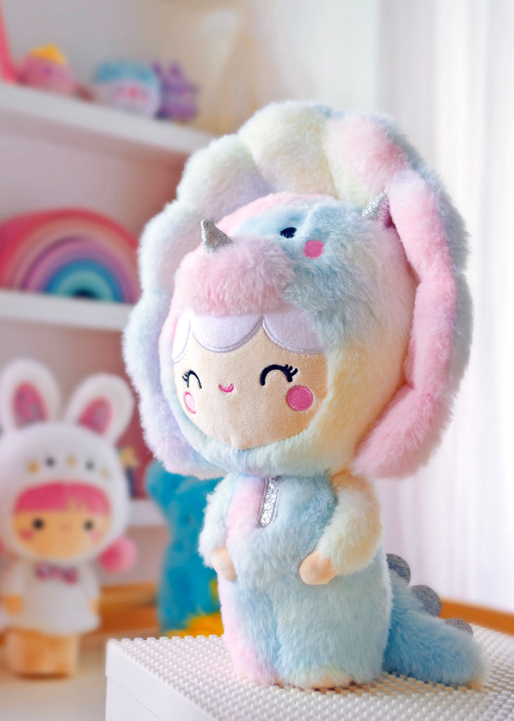 Roarsome Rainbow Momiji doll, 12.5", in pastel dino suit with silver horn, smiling in a bright colorful children's room. — Momiji Doll