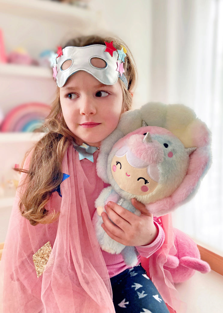 Momiji fan in a pink cape and silver mask hugs a 12.5" Roarsome Rainbow plush, looking aside with a slight smile. — Momiji Doll