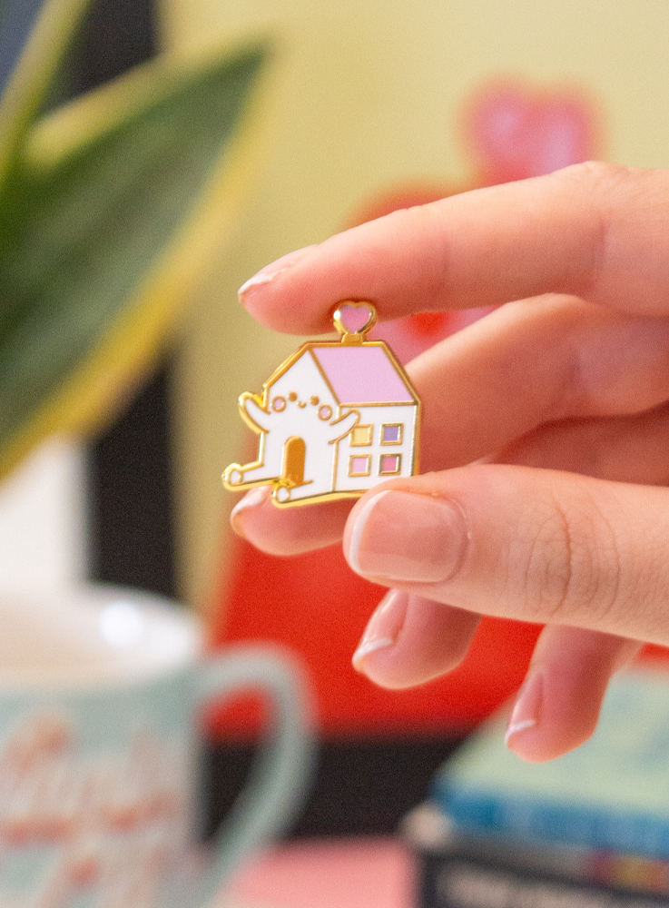 A hand holds the Happy Home Pin Momiji doll, a cute house-shaped character with open arms and legs, smiling joyfully. — Momiji Doll