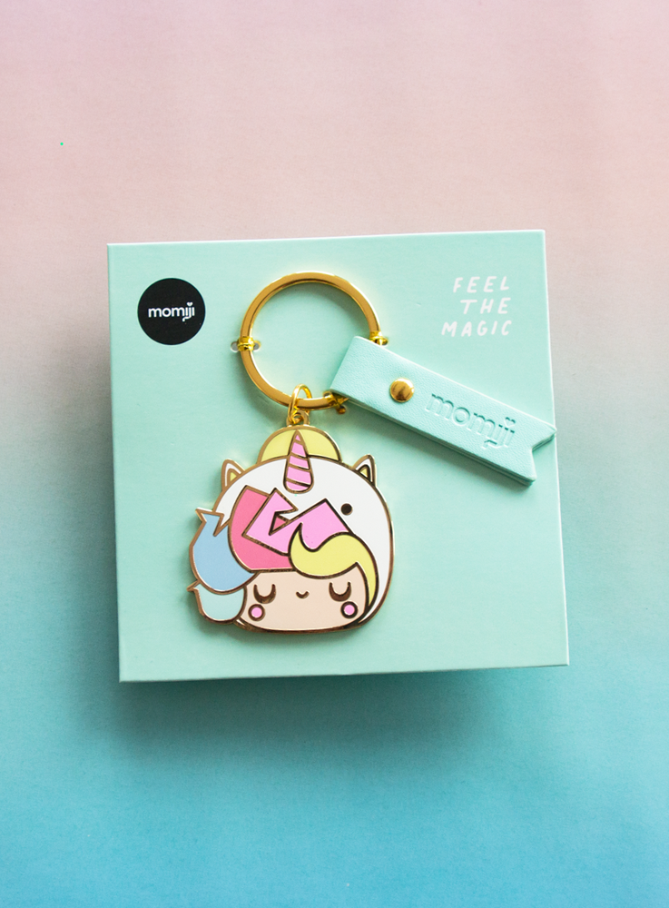 The Little Starlight Girl Momiji doll keychain with gold accents and a “feel the magic” card on a blue-pink gradient surface. — Momiji Doll
