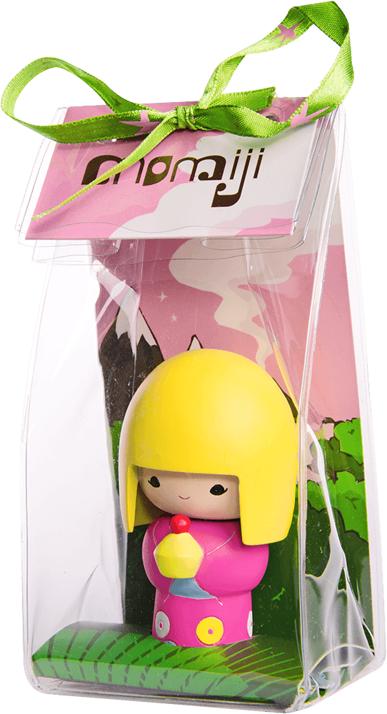 Pixie Momiji doll with yellow hair and pink outfit, displayed in a clear box with a green ribbon and vibrant backdrop. — Momiji Doll