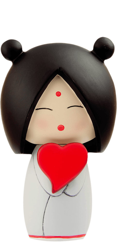 The I heart U Momiji doll has black hair, closed eyes, a red dot on its forehead, and holds a bright red heart. — Momiji Doll