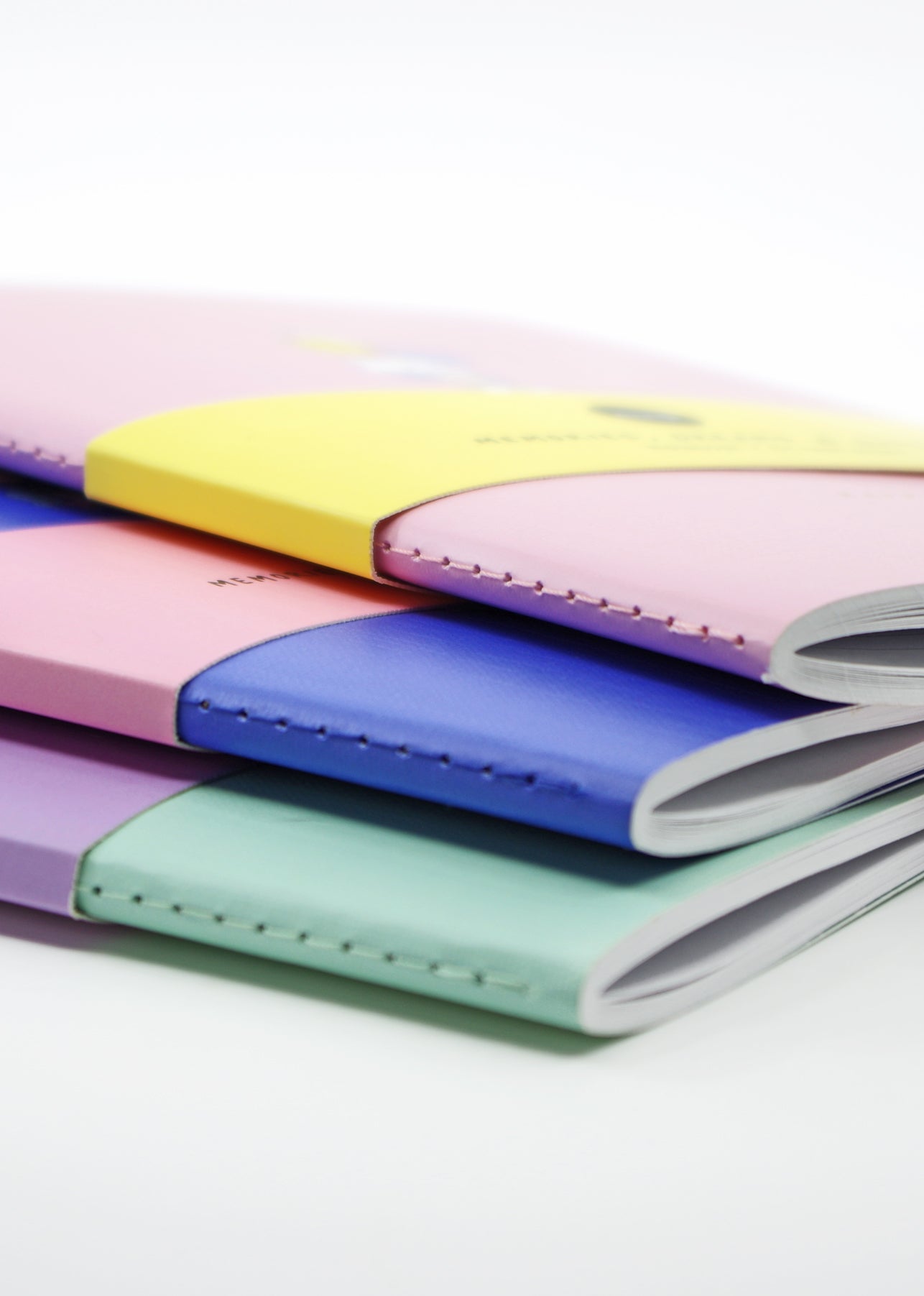 A close-up of four Good Vibes Gang Momiji doll notebooks with textured linen covers stacked on a white background. — Momiji Doll