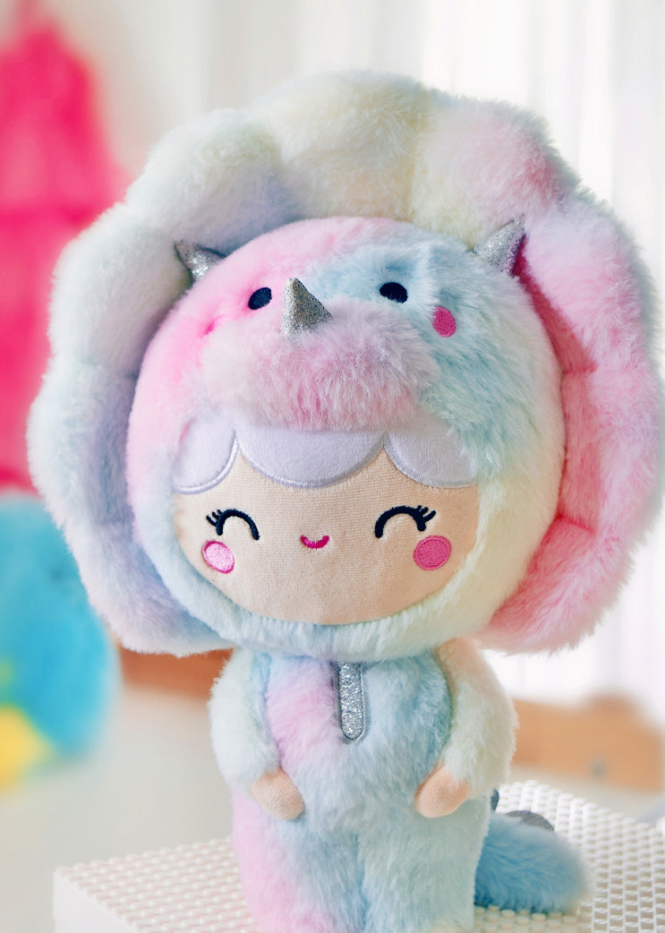 Roarsome Rainbow Plush Momiji doll with pastel colors, smiling face, and a dinosaur hood topped by a shiny silver horn. — Momiji Doll