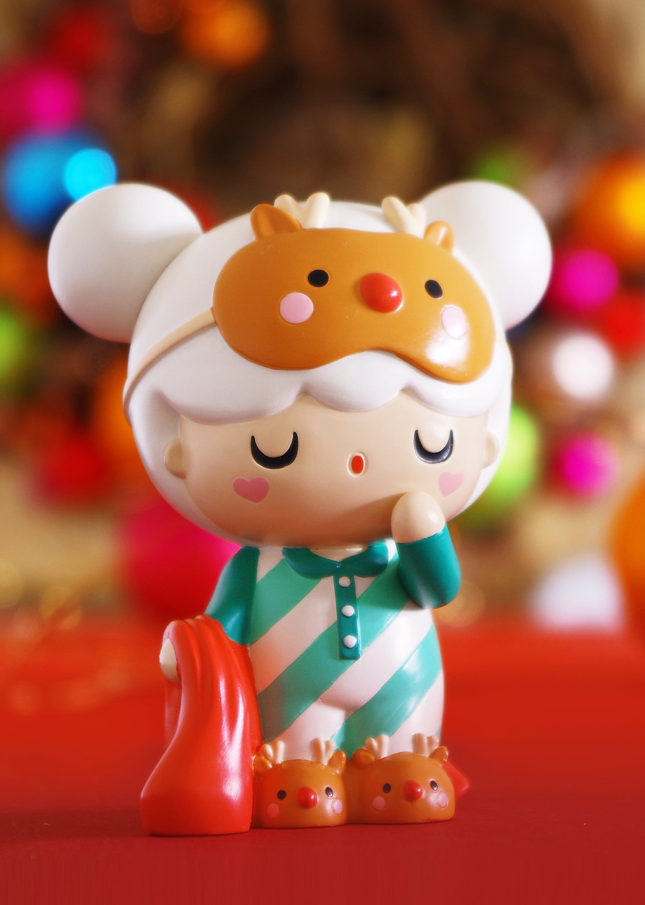 Dear Santa Momiji doll in striped pajamas, reindeer slippers, mask, and red blanket on a bright, colorful background. — Momiji Doll