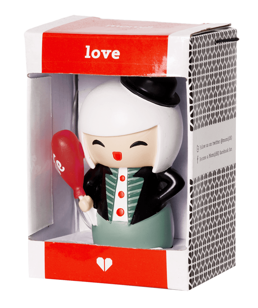 A Momiji doll with white hair, black hat, and green outfit holds a red heart gift in a box labeled "Love. — Momiji Doll