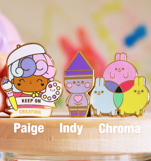 Three Create | Big Ideas 2020 Momiji doll enamel pins with colorful character designs, shown against a blurred background. — Momiji Doll