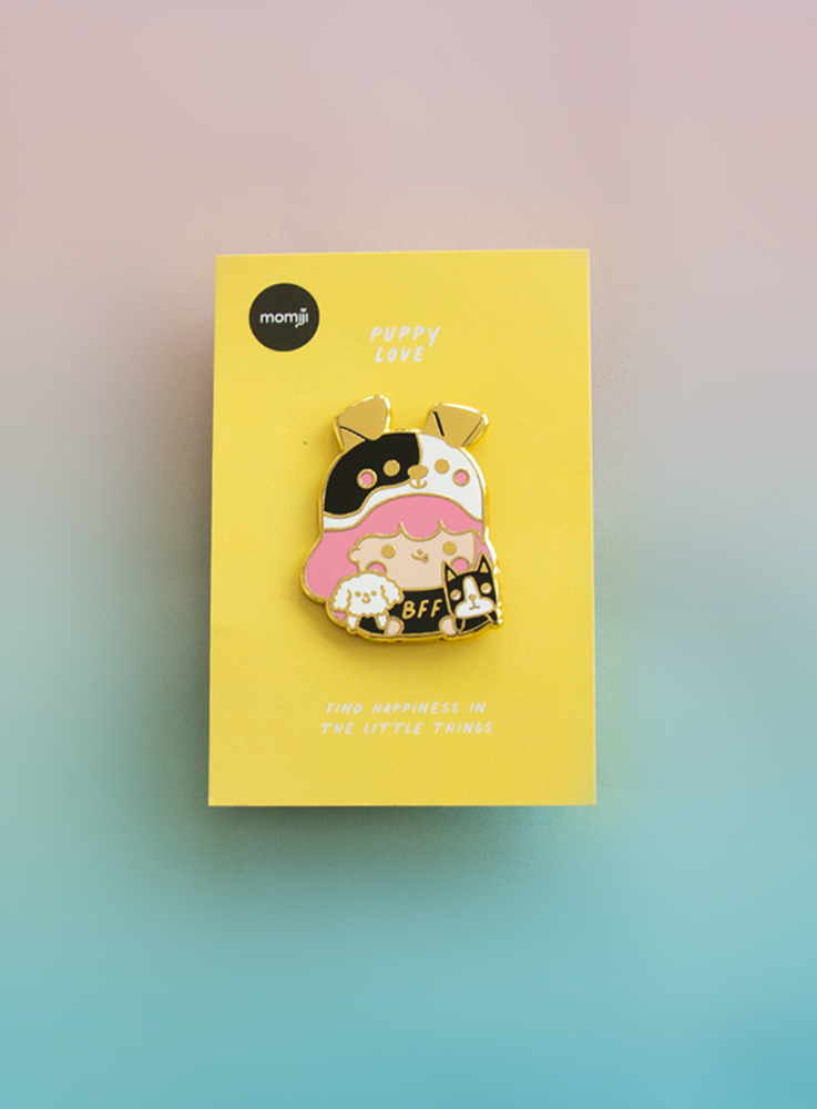 The Puppy Love Pin Momiji doll wears a cute puppy costume, displayed on a yellow card with "Find happiness in the little things. — Momiji Doll