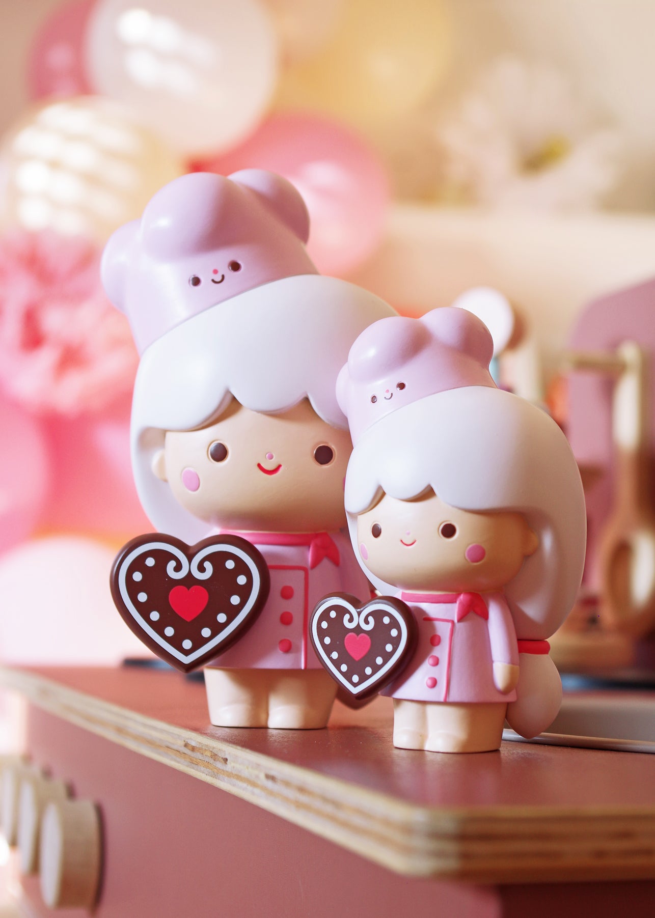 Two Sweetie Momiji dolls in pastel chef outfits, pink hats, each holding a heart cookie. Cute baking-themed collectible dolls. — Momiji Doll