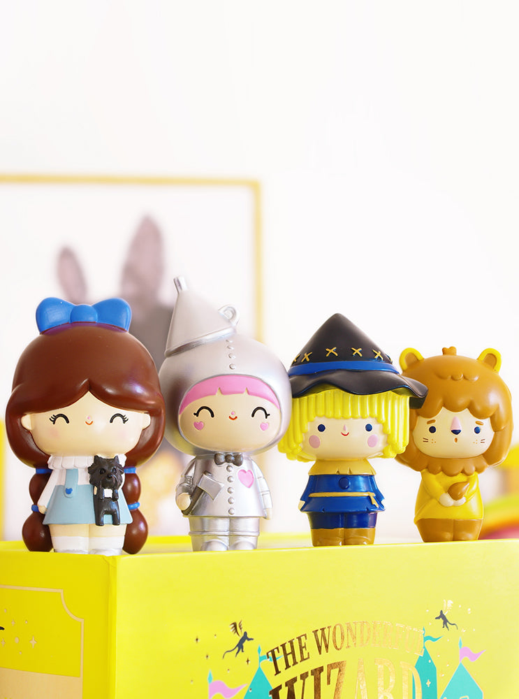 Four Wizard of Oz Momiji dolls—Dorothy, Tin Man, Scarecrow & Lion—stand on The Wonderful Wizard of Oz book. — Momiji Doll
